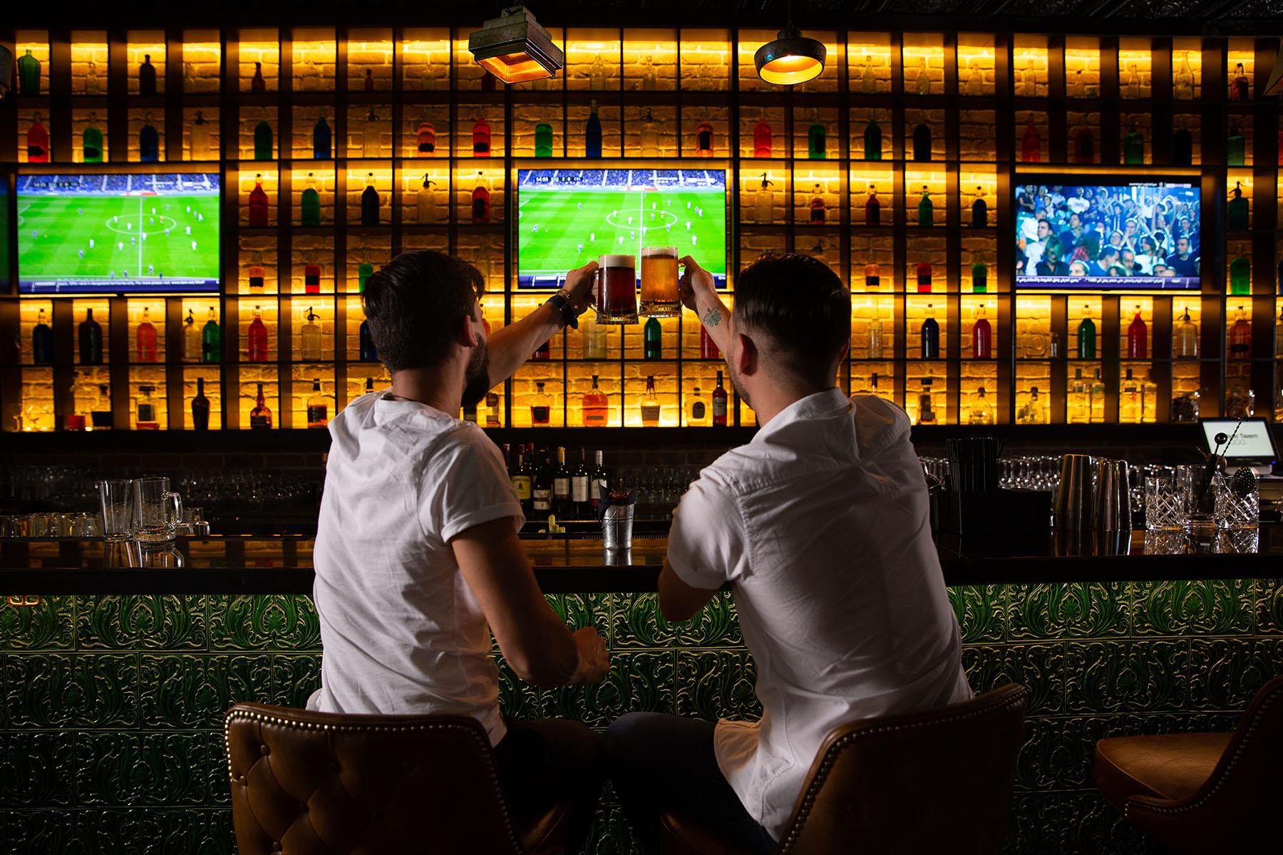 男人们在酒吧欢呼，背景是足球比赛